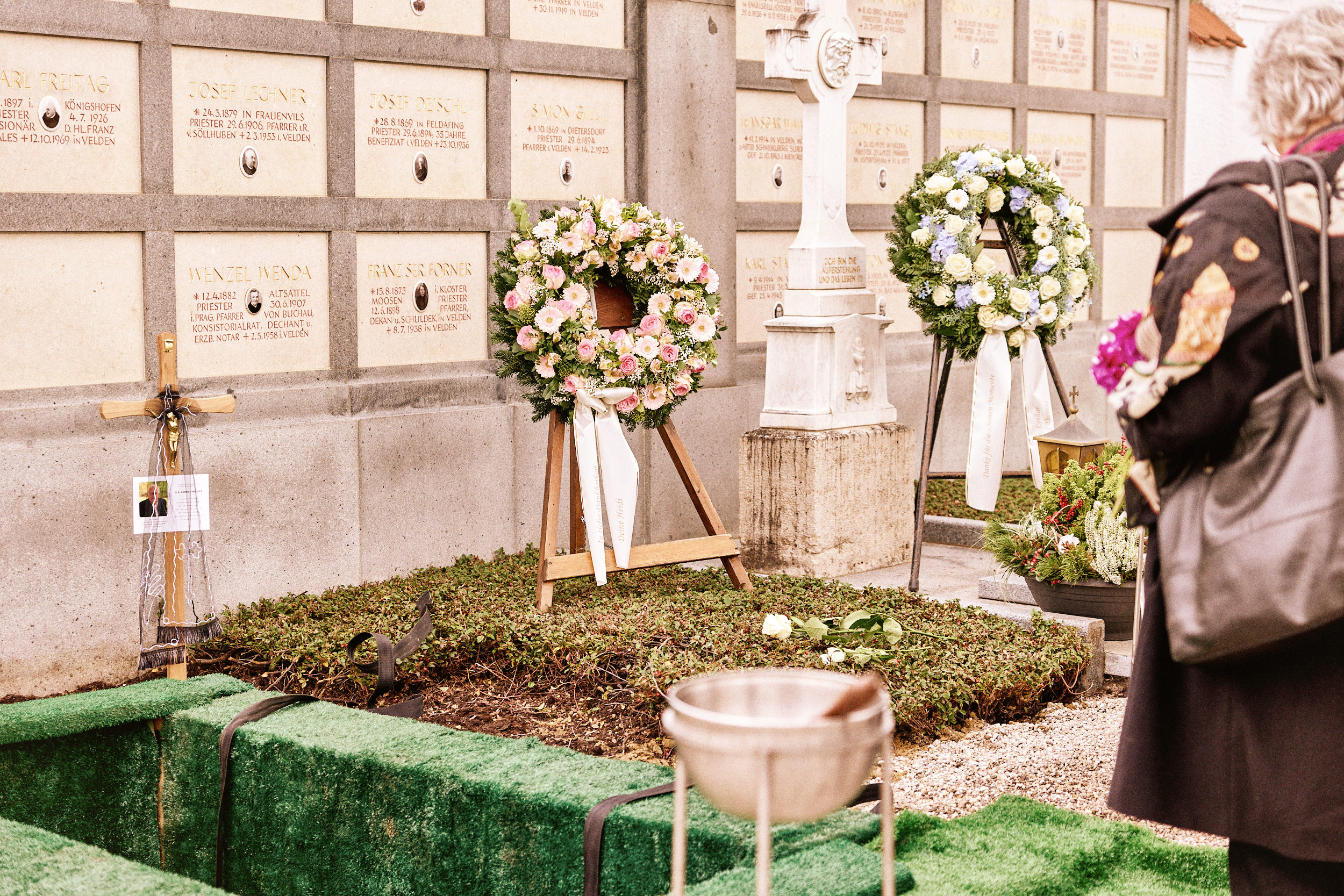 Grabfeld mit Kränzen und Gestecken auf einem Friedhof in Niederbayern